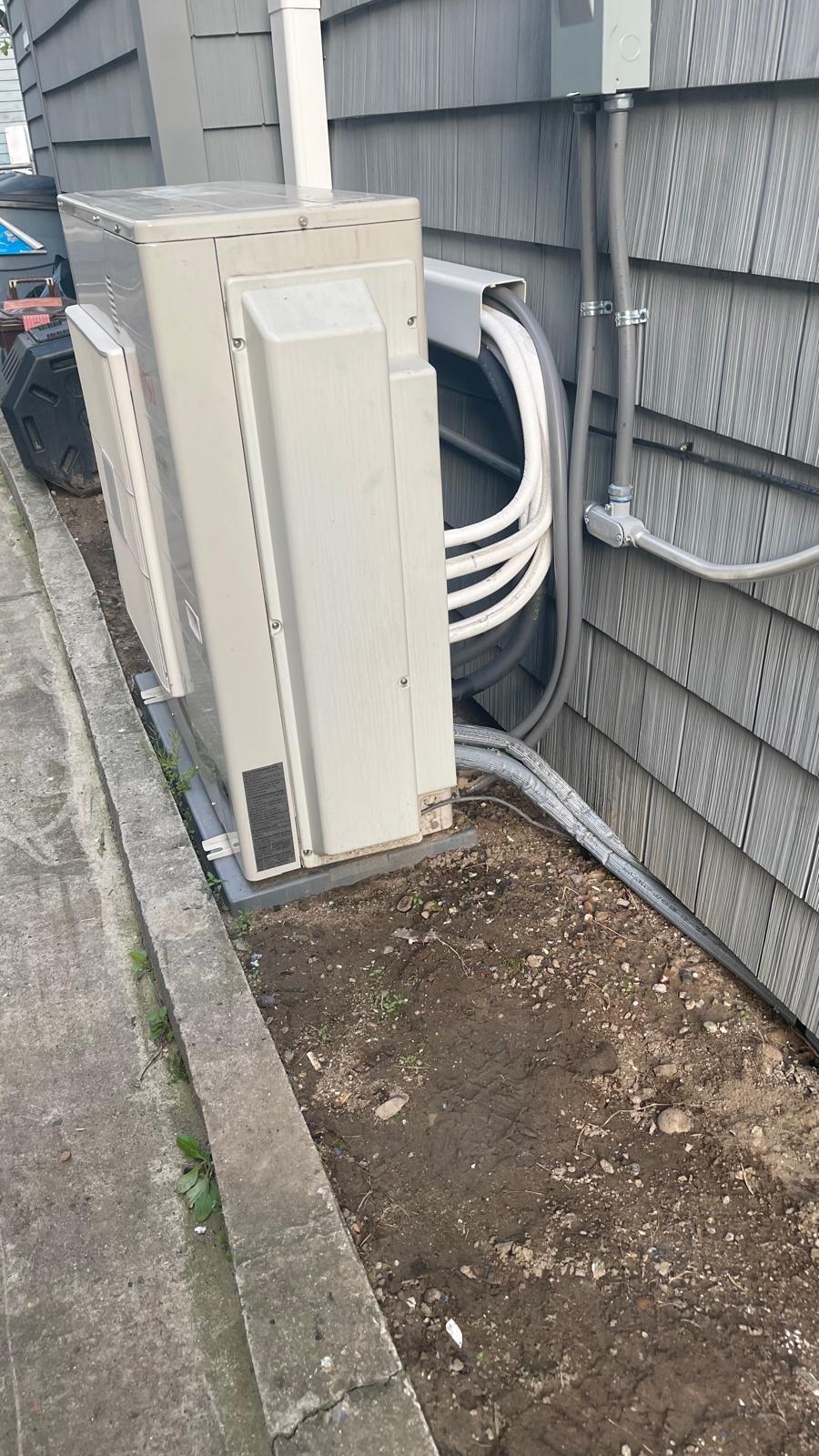 Outdoor heat-pump unit with refrigerant lines and electrical conduit on a side wall