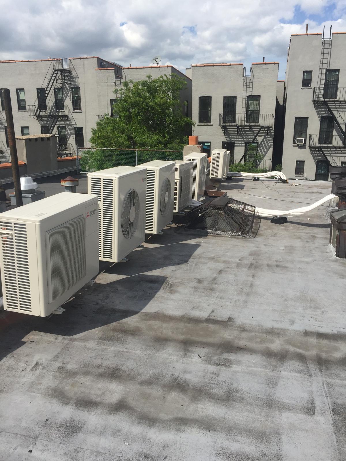 Row of Mitsubishi outdoor heat-pump units on a New York rooftop